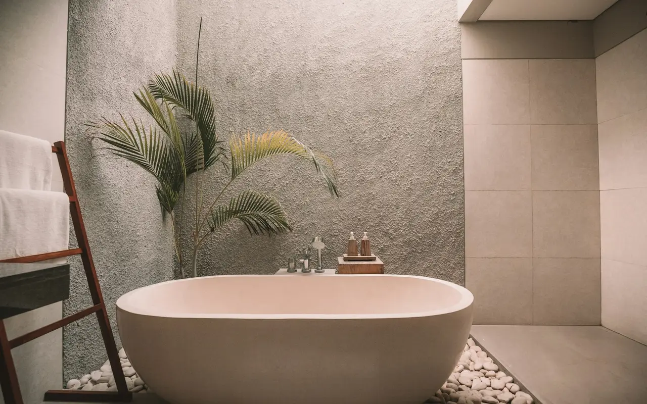A bathtub, towels and stones in a stone-coloured room, with no people.