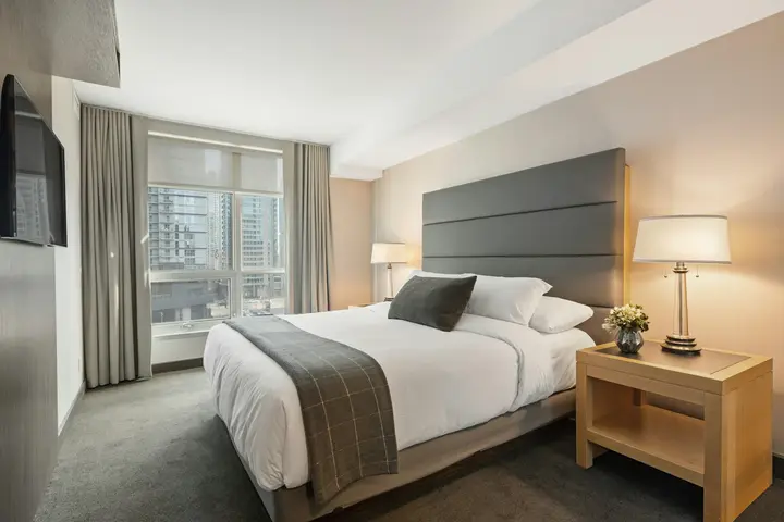 Quarto de hotel com linho branco e uma flor, sem pessoas.